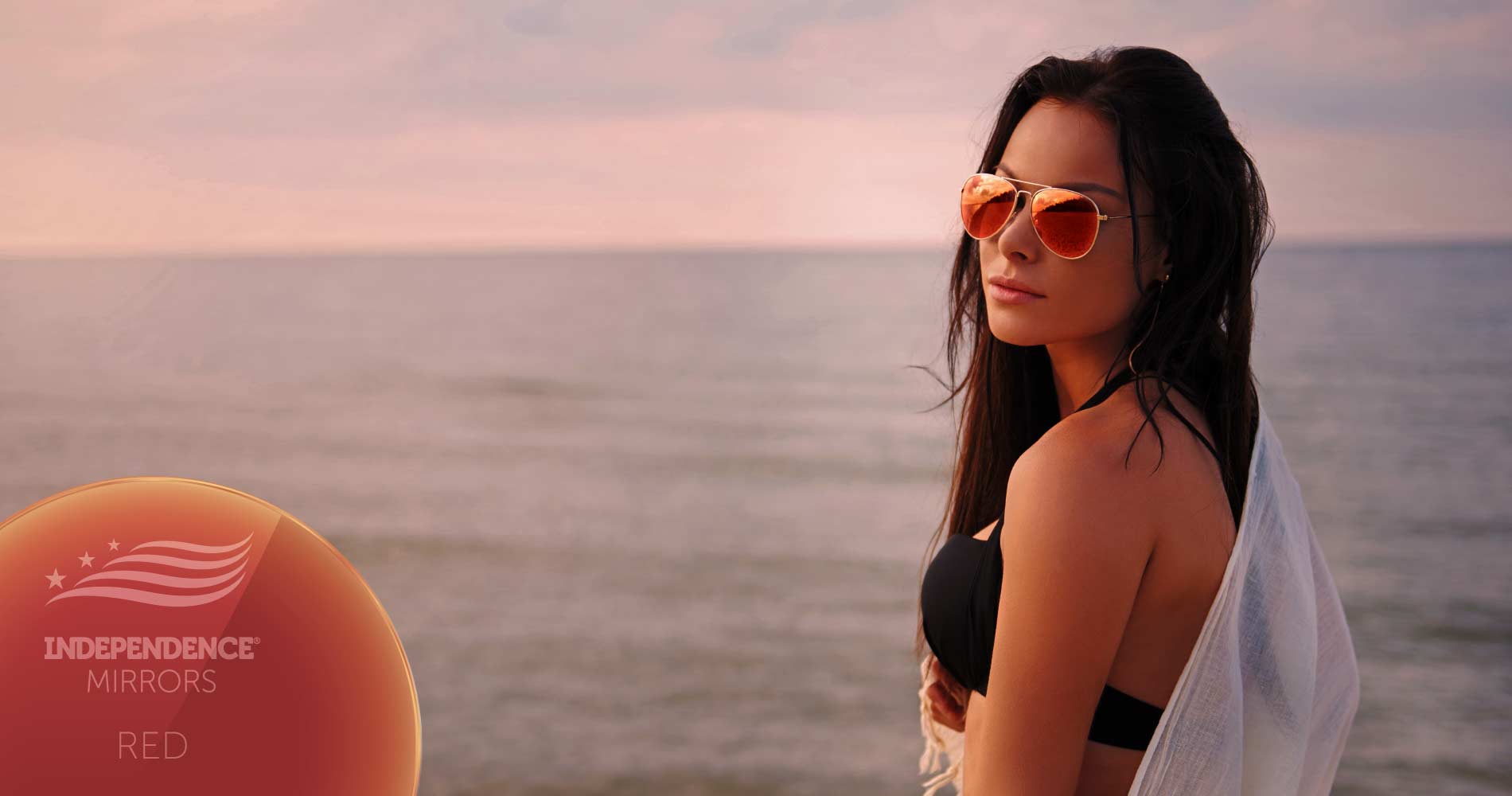Woman on the beach at sunset wearing red-colored mirrored sunglasses