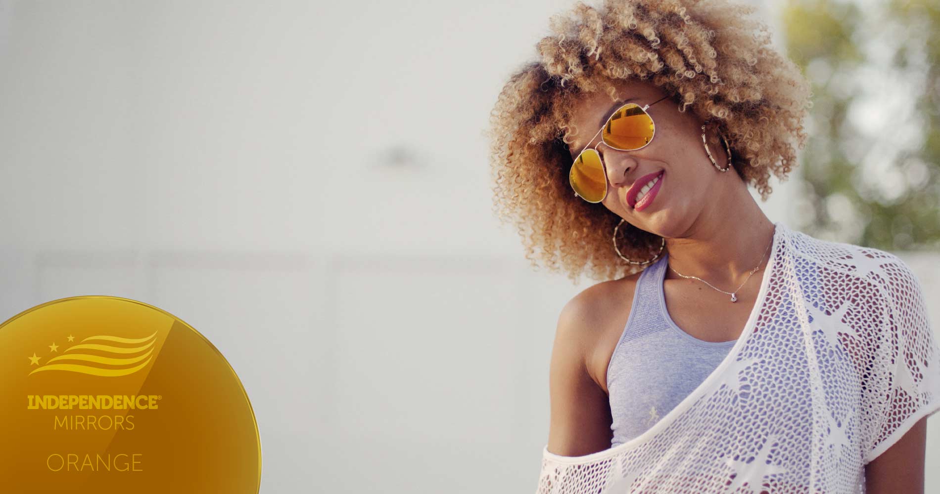 Young woman smiling wearing orange-colored mirrored sunglasses